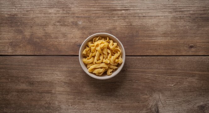 Overhead image of dry trofie pasta arranged in a bowl on a weathered wooden table