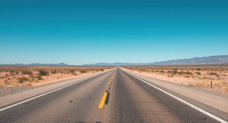 Open desert roadway extending to distant horizon with clear sky and generous copy space