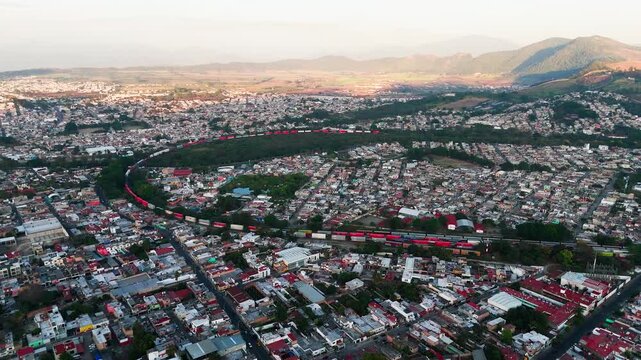 Aerial footage showing a long freight train moving through the city of tepic in nayarit, mexico
