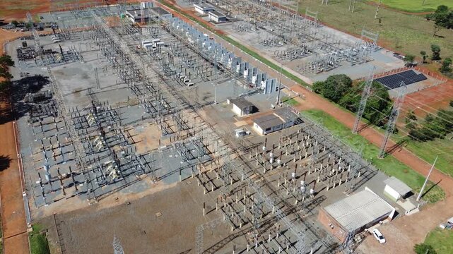 Aerial drone tracking shot slowly passing over a massive electrical transformer station with a tilt down to reveal complex power grid infrastructure in Goiania, Brazil.