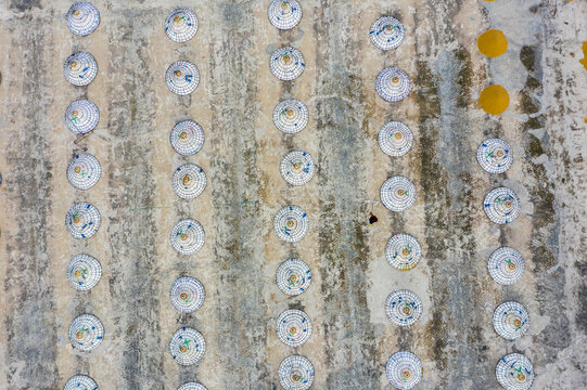 Aerial view of circular objects with white, blue and yellow colors evenly spread across a textured surface, Brahmanbaria, Bangladesh.