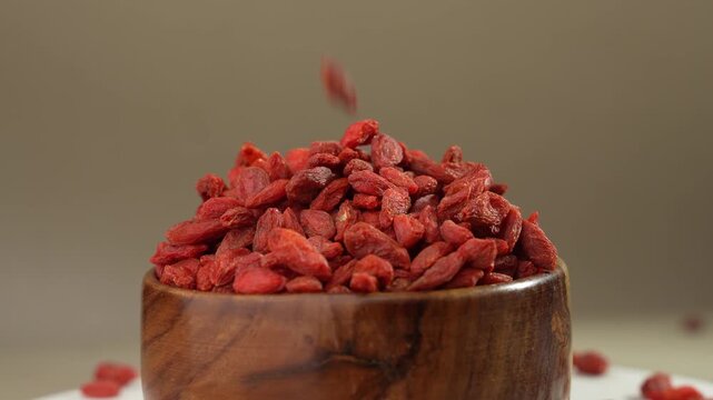 Dried Goji berries or Wolfberry falling on wooden bowl.