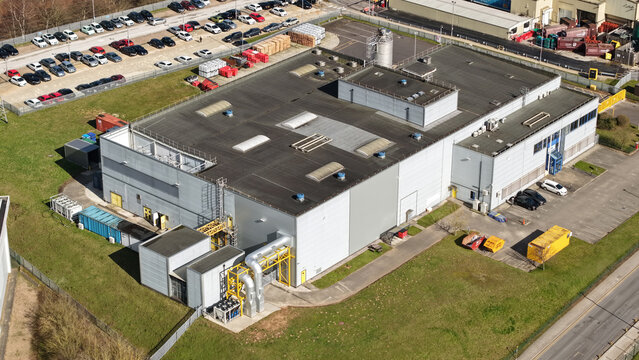 Aerial view of a large, modern industrial building with a flat roof and surrounding green space and parking lot, Worksop, England, United Kingdom.