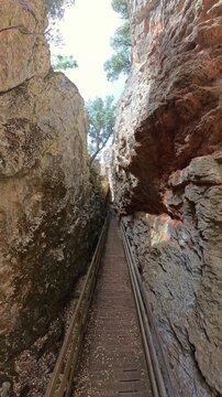 Narrow wooden path leading through the impressive rock formations of Quebrada del Toro gorge, offering hikers an adventurous experience in Lagunas de Ruidera Natural Park. Ossa de Montiel, Albacete
