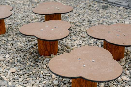 Unique flower-shaped tables on gravel surface in outdoor setting