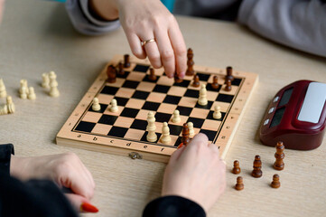 Hands of players move chess pieces on wooden board during game © bo.kvk