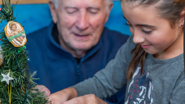 An elderly gentleman with his nephew at home decorating Christmas Tree