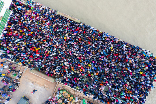 Aerial view of a vibrant tapestry of people congregating at the bustling Mawa ferry terminal, where the river meets the shore, Mawa, Dhaka Division, Bangladesh.