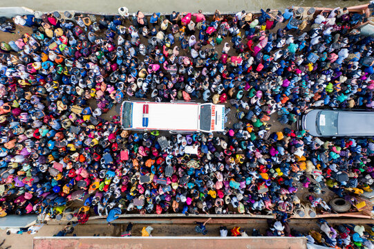 Aerial view of a tightly packed crowd surrounding vehicles, a vibrant tapestry of colors against the muted backdrop, Mawa, Dhaka Division, Bangladesh.