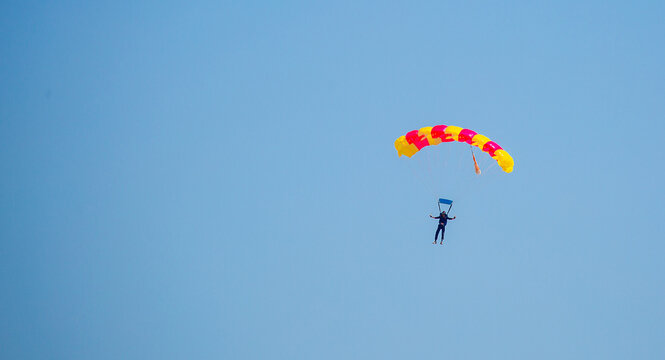 Skydiving. Flying parachutists against the background of the blue sky and mountains. Extreme sport and entertainment.