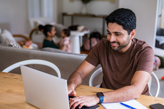 Indian man working on his laptop on the dining table inside home