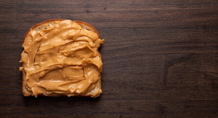 Fototapeta premium Peanut butter and banana toast served on a dark wood surface for a wholesome treat