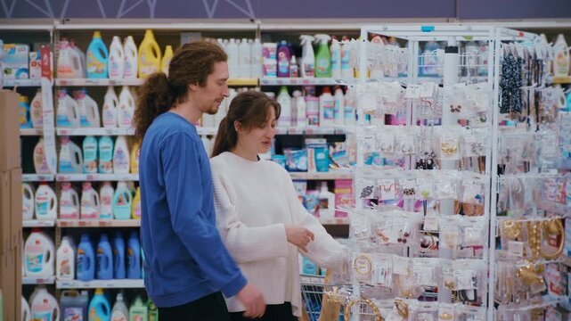 Joyful young couple choosing jewelry together in a hypermarket aisle during their shopping