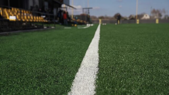 The sideline marking the edge of a soccer field against the background of football players training in preparation for a football match at the stadium.
