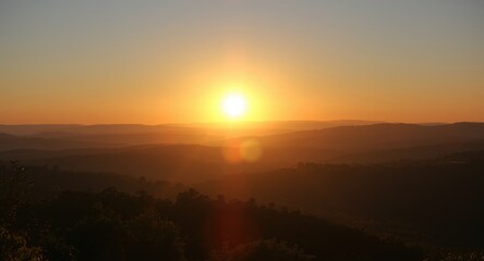 Fototapeta premium Radiant summer solstice sun rising above peaceful valley and hills