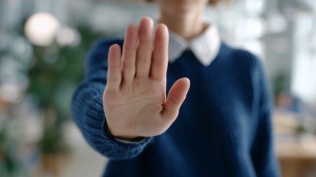 Female human resources manager showing palm of hand in stop gesture at modern office background, concept for workplace harassment prevention, declining proposal and setting boundaries