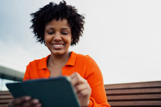 Close up of happy attractive woman smiling while looking at digital tablet, cheerful student learning online, digital connectivity, remote work, authentic representation, real people.