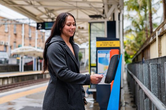 Mixed race woman tapping contactless card on ticket machine at the train station