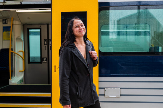 A woman steps off a train at a station while it rains in New Zealand