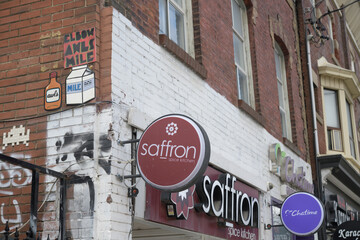 Naklejka premium wall mounted round projecting sign outside Saffron Spice Kitchen, a Sir Lankan restaurant, located at 459 Queen St W, Toronto