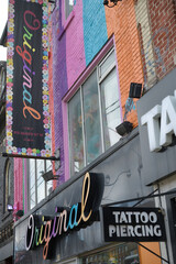 Naklejka premium projecting Tattoo/Piercing sign and exterior building signs of Original, a women's clothing store, 515 Queen St W, Toronto