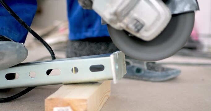 Worker in Blue Suit Cutting Metal Bracket with Angle Grinder and Flying Sparks for Industrial Safety Training and Metallurgy Research in Structural Maintenance and Mechanical Repair Engineering