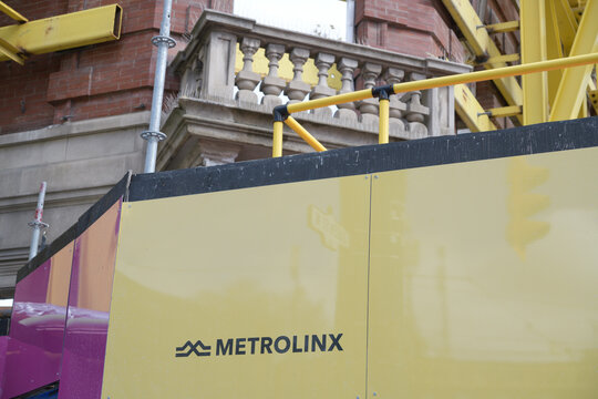hoarding outside construction site of future Queen-Spadina station, Ontario Line, with logo sign of Metrolinx, Toronto