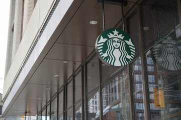 Naklejka premium ceiling mounted suspended sign with round Starbucks Coffee Company Mermaid logo outside 123 Portland St, Toronto