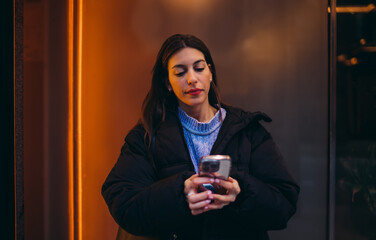 Professional millennial woman using smartphone near modern office, mobile business communication,...