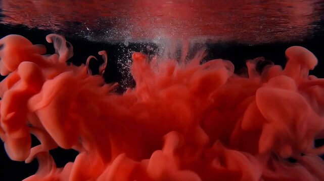 Red ink swirling in water against a black background.