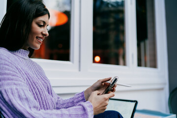 Fototapeta premium Smiling female user typing on digital tablet with stylus in hand. Financial technology, online banking, data processing or creative editing. Modern professional working in wooden textured office.