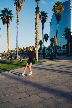 Woman on roller skates shifts weight with one leg extended and phone held, combining motion precision, mobile engagement, and expressive movement in urban action flow.