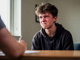 Fototapeta premium Angry frustrated teenage boy arguing with therapist or parent concept of youth rebellion anger management family conflict mental health