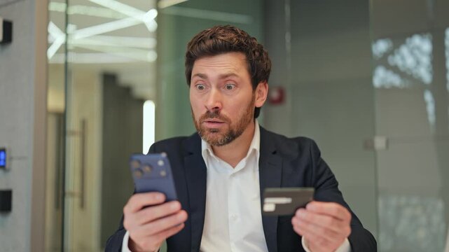 Businessman engaging in online transaction with phone and credit card. Expresses initial happiness, then shock, then deep confusion and concern, possibly due to unexpected issue.