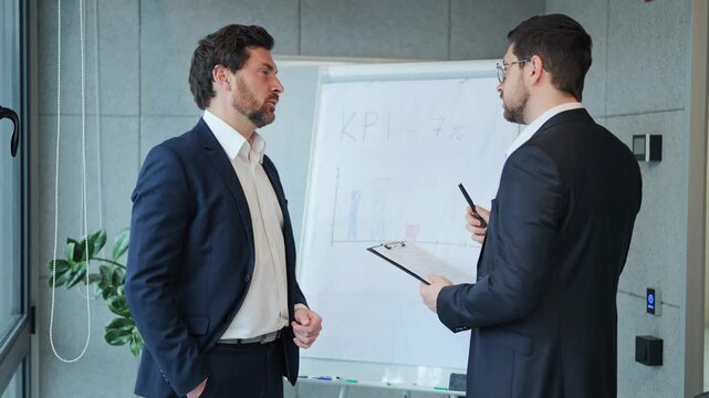 Professional individuals deeply engaged in analyzing business performance. Focused expressions demonstrate commitment during discussion of key performance indicators.