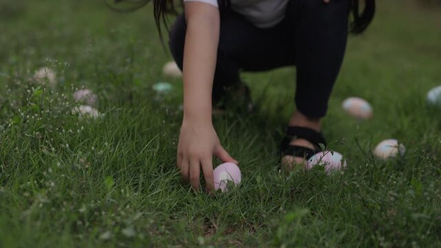 slow motion of child girl walking and hunting for Easter eggs on green grass in the garden
