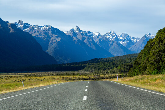 Low angle of bitumen road towards snow-capped mountains