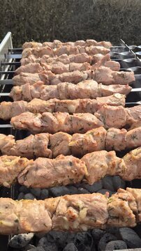The kebabs are grilled on the coals while rotating.