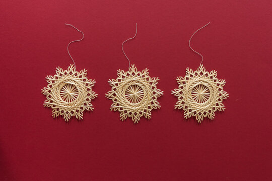 Snowflakes are made of straw on a red background. Straw star. Christmas decor. Top view. Straw weaving