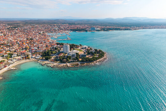 Wide aerial panorama of Vodice coastline with Heksagon beach, turquoise Adriatic Sea and dense town with marina in the background