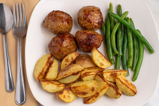  meat balls and potato wedges with green beans