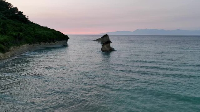 Aerial drone footage flying over the beach and sea stacks of Canal d'Amour, Sidari. A beautiful, calm sunset over the Ionian Sea, Corfu, Greece