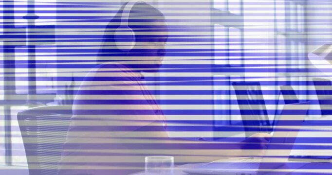 Woman wearing headphones at office, joining call, typing on laptop, scan-lines obscuring