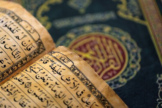 Pages of Al Quran Muslim holy book on table in mosque. Details of arabic calligraphy on islamic book close up. Concept of Islam religion and praying in arabic countries