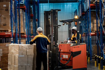 Obraz premium Rear view of logistics manager checking commercial package pallet while forklift operator giving thumbs up. Safe transport and inventory distribution in modern factory storehouse.