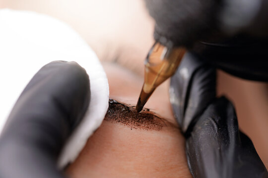 closeup of eyebrow microblading procedure with precision tool, master view point