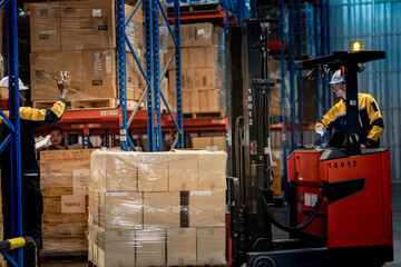 frican American warehouse worker raising hand to guide Caucasian forklift driver. Professional industrial team communicating for safe cargo pallet transport in distribution center.