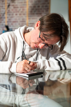jeune homme prenant des notes sur un bloc-notes avec un styloe