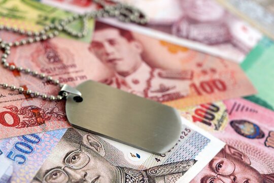 Thai baht currency money bills and military token close up. The concept of army service