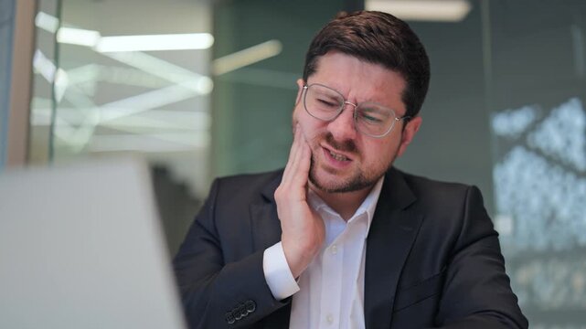 Professional experiences severe toothache, enduring sharp pain. Dental problem causes discomfort, visible suffering. Worker affected by oral health issue working, showing distress, needing relief.